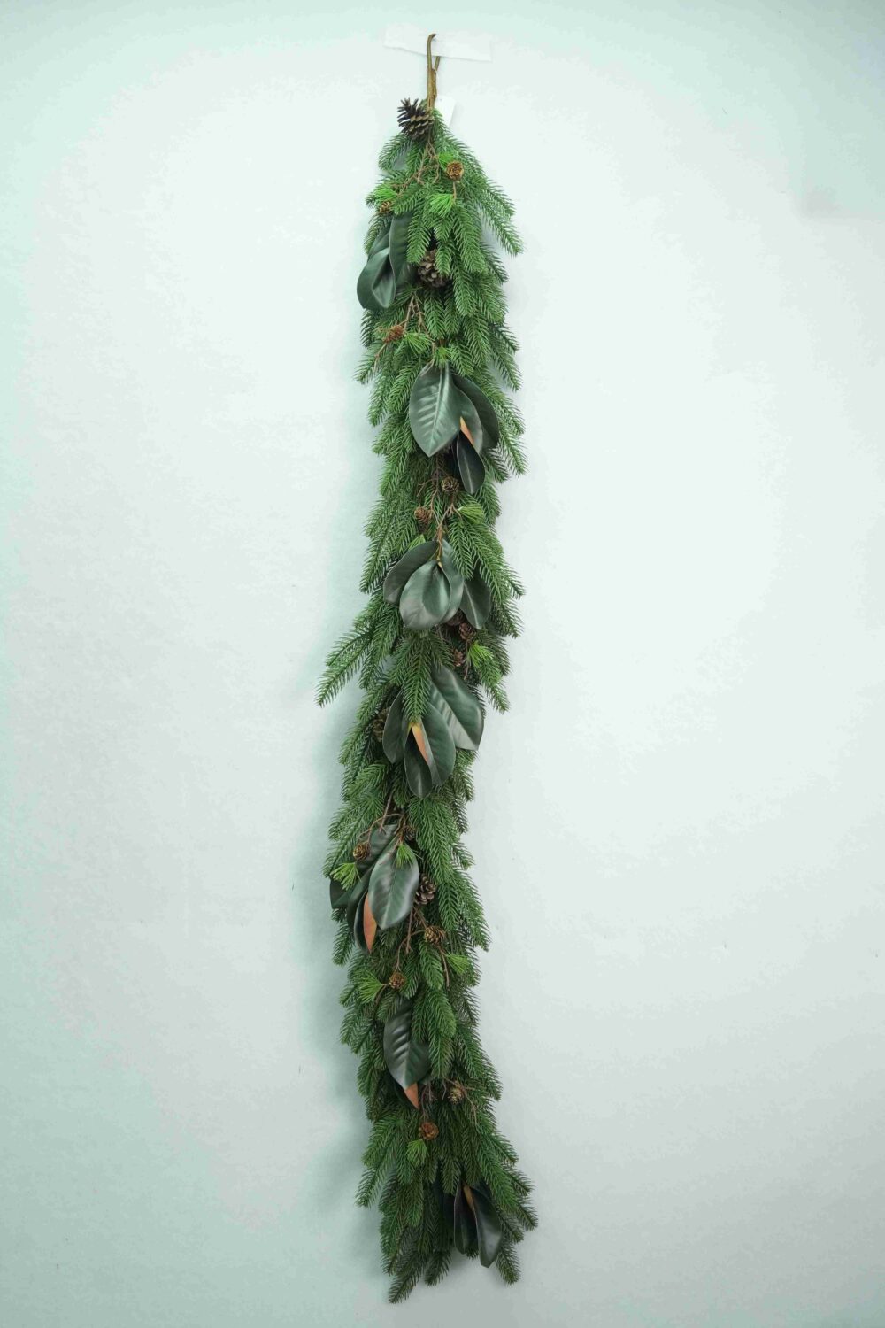 Gesamtansicht einer künstlichen, gemischten immergrünen Weihnachtsgirlande mit herabfließendem Grün und breiten botanischen Blättern