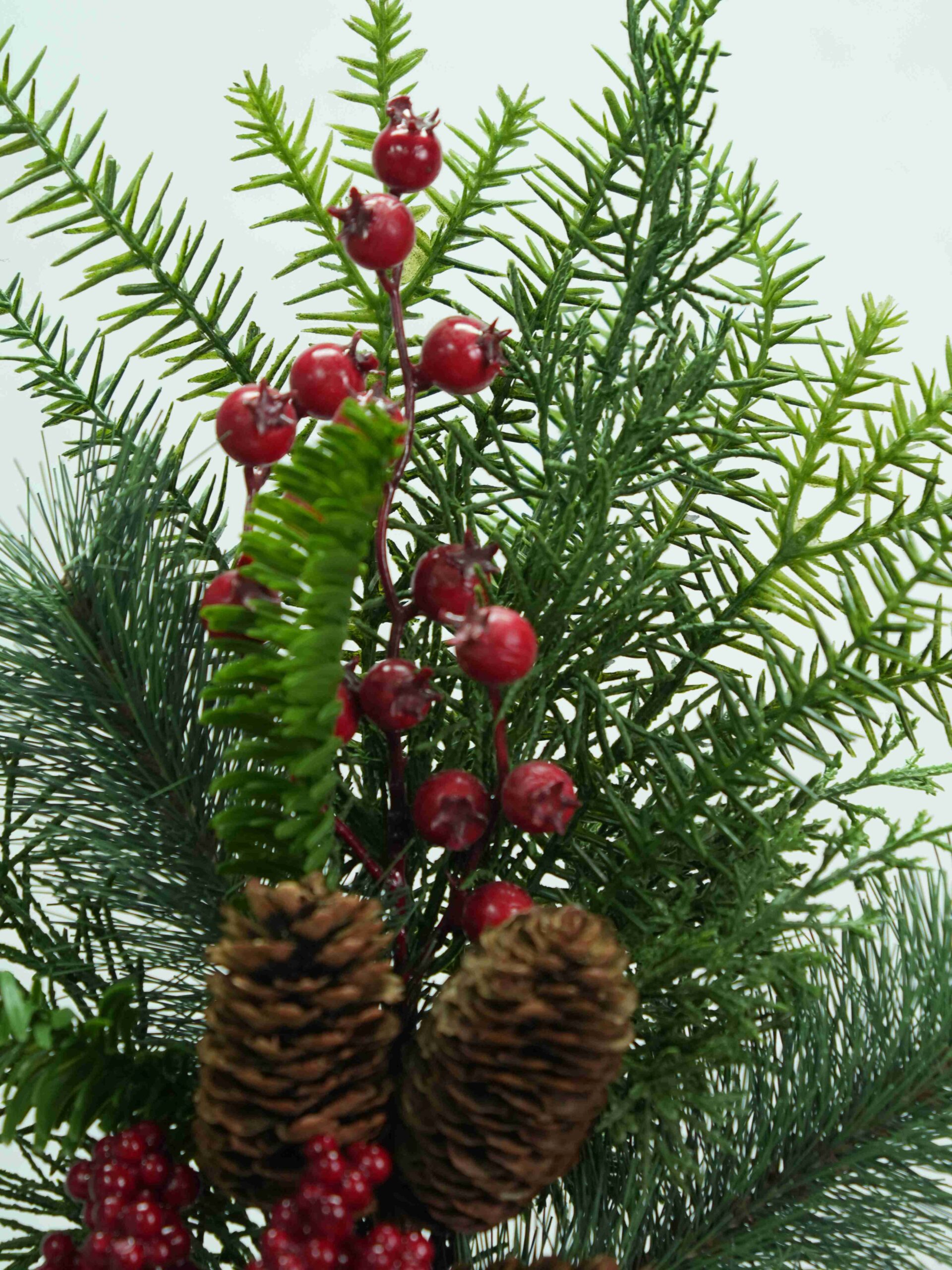 Detailed view of festive red berry clusters contrasting with fine green evergreen foliage on holiday pick