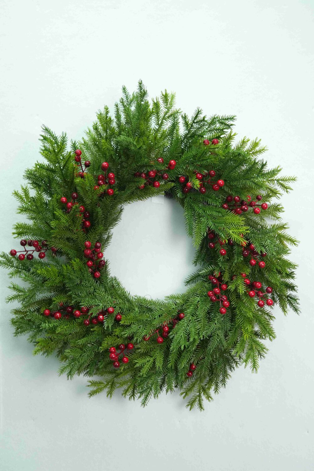 Gesamtansicht eines künstlichen immergrünen Weihnachtskranzes mit natürlich wirkendem, gedrehtem Rankenfuß und grünem Beiwerk