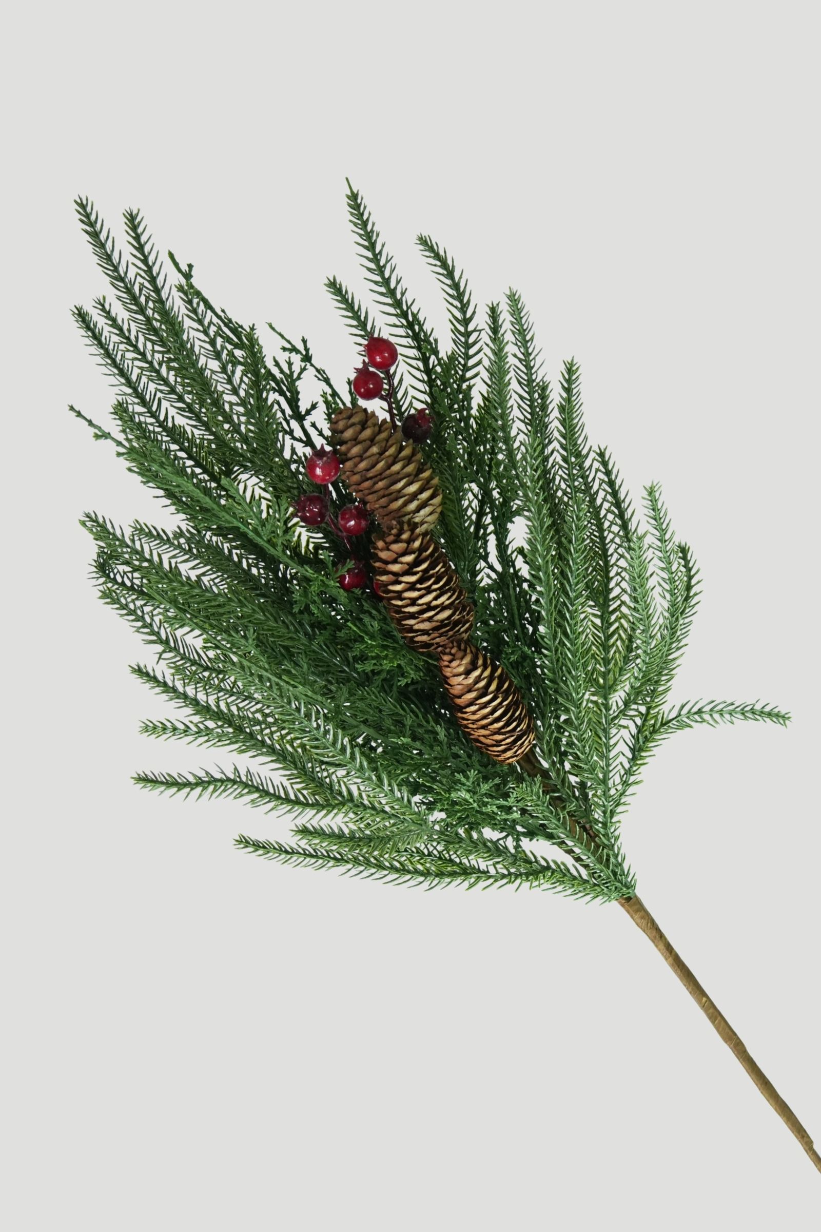 Angled view of green evergreen branches with red berry and pinecone accents